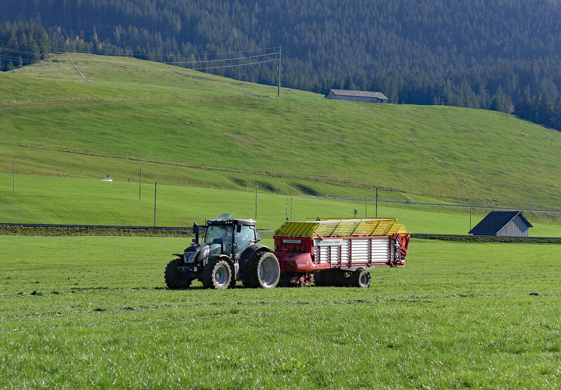Traktor mit Ladewagen auf einer gemähten Wiese